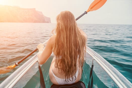 Woman in kayak back view. Happy young woman with long hair floating in transparent kayak on the crystal clear sea. Summer holiday vacation and cheerful female people having fun on the boat.