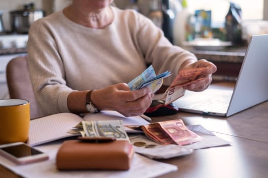 Portrait of an old woman counting money. The concept of old age, poverty, austerity.