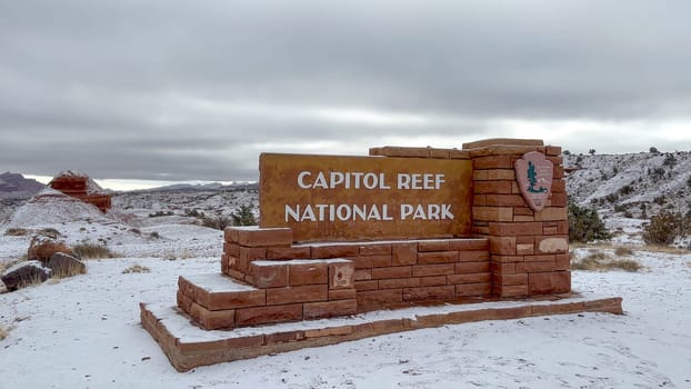 Torrey, Utah, USA - 03.03.2024: Capitol Reef National Park Entrance sign on a cloudy winter day. There is snow on the ground and the sky is overcast.