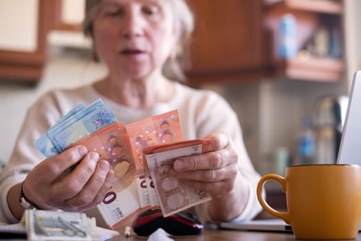 Portrait of an old woman counting money. The concept of old age, poverty, austerity.