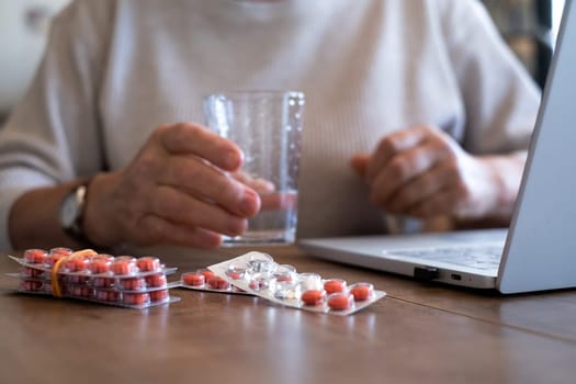 Senior woman takes pill with glass of water in hand. Stressed female drinking sedated antidepressant meds. Woman feels depressed, taking drugs.