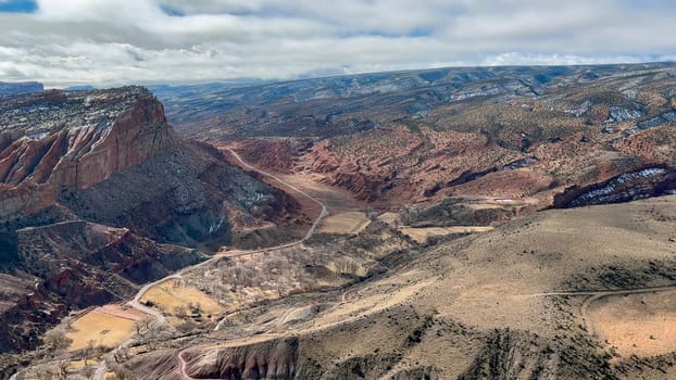 Breathtaking aerial perspective of Capitol Reef National Park, showcasing its vast desert landscapes, towering red rock cliffs, and winding canyons. The Waterpocket Fold is clearly visible - Utah, USA