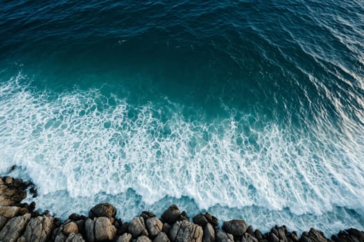 This captivating aerial image showcases the serene beauty of a sandy beach with the ocean's waves gently rolling onto the shore. The breaking waves create a white, frothy pattern along the water's edge, adding a touch of dynamic energy to the tranquil scene.