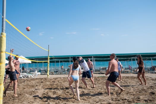 Tourists play beach volleyball on the sea during vacation, background of a clear blue sky while relaxing on the beach of the Green Max Hotel, Belek, Turkey, May 31, 2024