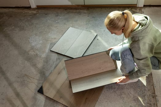 Interior Decorator Holds Luxury Vinyl Wood Samples On Concrete Floor In Condo. Selecting Waterproof Flooring. Home Reconstruction. Vinyl Tiles Collection, Patterns. Interior Design Idea. Horizontal