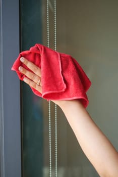 close up of person hand in gloves cleaning window glass .