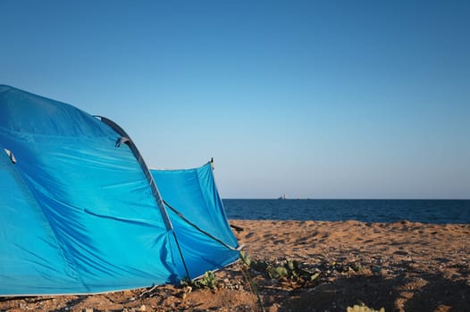 Tent on the sandy beach by the sea. Nobody. A colorful tent to protect from the wind, the sun and to sleep in.