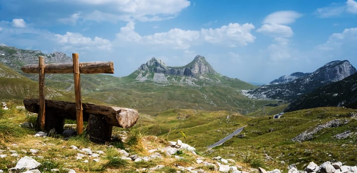 Scenic wooden bench in mountains of Montenegro in National park Durmitor with beautiful nature view. Amazing balkan landscape in sunny summer day