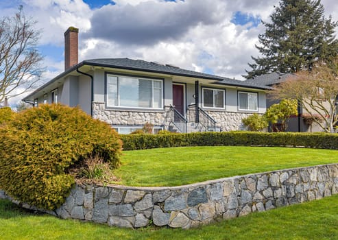 Average residential house with green lawn on land terrace in front.