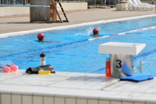 Swimmers wearing silicone caps compete in a pool