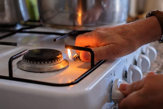 senior hand adjusting gas burning from a kitchen gas stove.