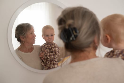 A cute little girl and her grandmother looking at mirror spending time together