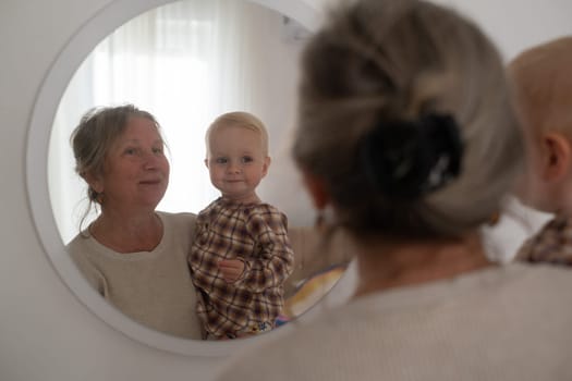A cute little girl and her grandmother looking at mirror spending time together