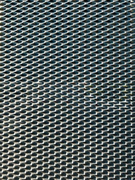 Close-up of a metal surface with a repeating pattern, capturing the interplay of light and shadow, emphasizing texture and industrial design.