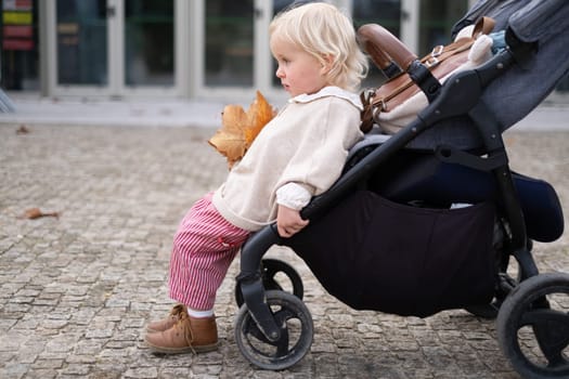 Little baby girl sitting in a chair in a baby carriage being tired