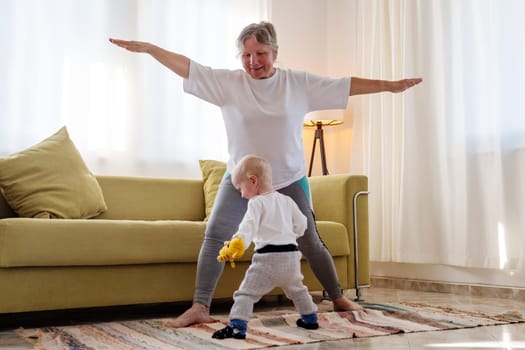 Senior caucasian woman doing yoga at home using chair as a props.
