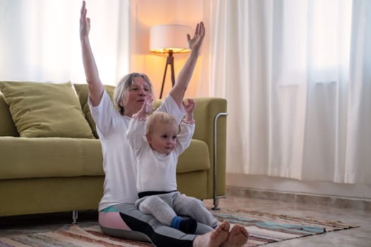 Senior caucasian woman doing yoga at home with a toddler