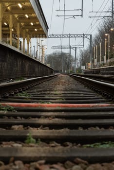 London, UK - Dec 25, 2023 - Railway iron rails from the low perspective. Railroad tracks with limited depth of focus, The Railway system with Metal frames of Train platform, Railroad track rails, Train tracks, Railway station, Space for text, Selective focus.