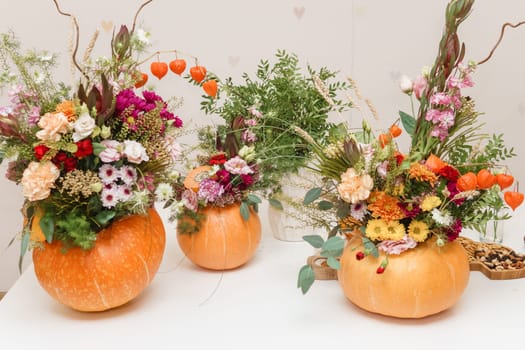Flower arrangement in a pumpkin, autumn interior decor. Creating handmade autumn decor