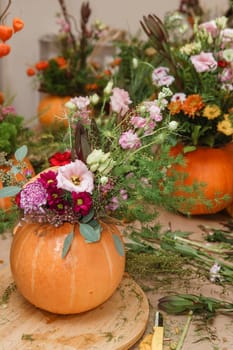 Flower arrangement in a pumpkin, autumn interior decor. Creating handmade autumn decor