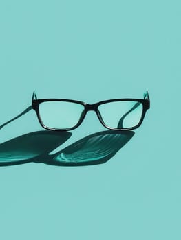 Black eyeglasses cast a long shadow on a light blue background.