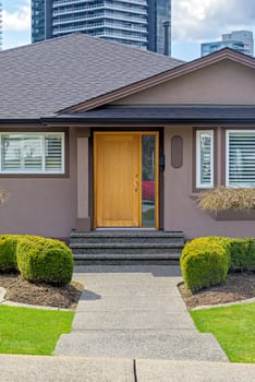 Neat entrance of a family house on residential high-rise buildings background.