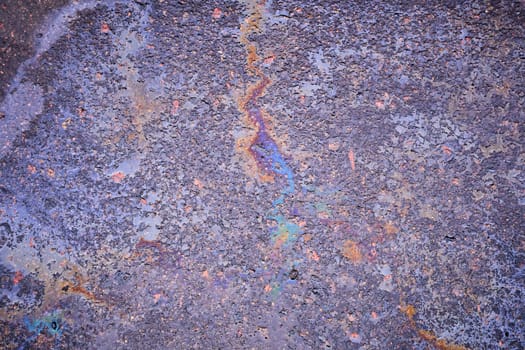 Petroleum fuel spilled on wet asphalt, abstract background.