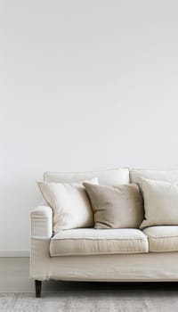 A white couch with three cushions sits in front of a white wall. The couch is on a light-colored rug.