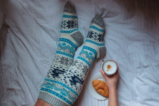 A young beautiful woman in warm handmade knitted clothes at home. . spring, winter season. Gaiters. Knee socks. Leggings.
