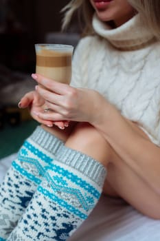 A young beautiful woman in warm handmade knitted clothes at home. . spring, winter season. Gaiters. Knee socks. Leggings.