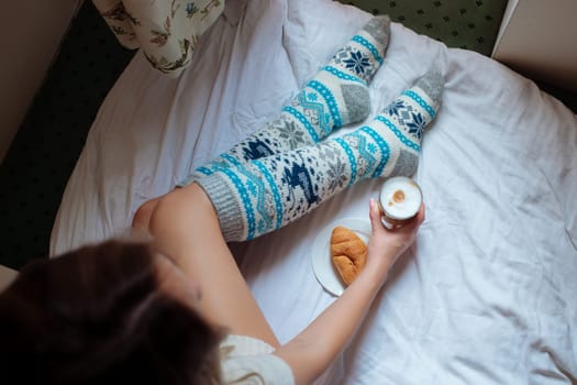 A young beautiful woman in warm handmade knitted clothes at home. . spring, winter season. Gaiters. Knee socks. Leggings.