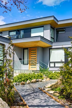 Neat entrance of modern residential house on blue sky background.