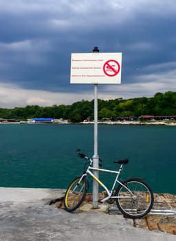 BULGARIA, VARNA - JUNE 06, 2013: 
bike near the warning sign on the dam by the sea in Varna, Bulgaria