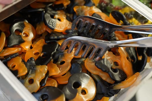 halloween orange and black gummy jelly candies in candy shop in plastic container. High quality photo. Halloween treat, holiday