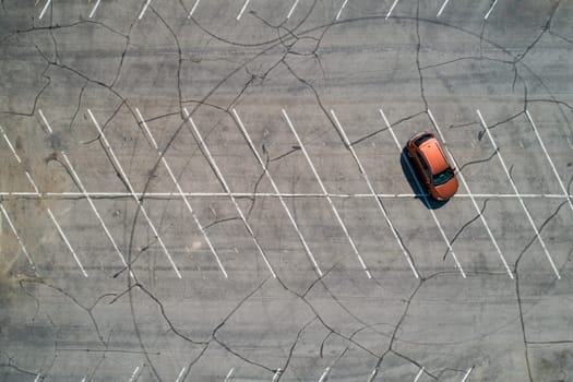 aerial view of a single car in an empty parking lot