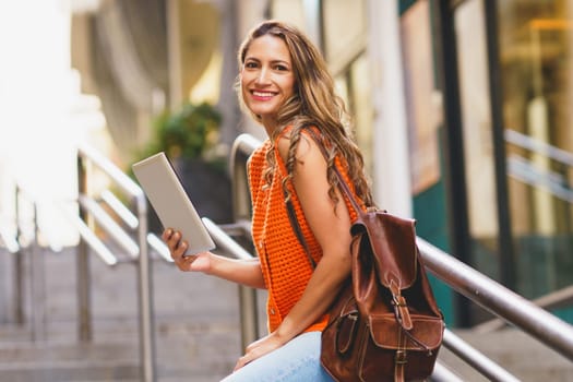 Beauty latin woman smiling at camera while standing using digital tablet in the city