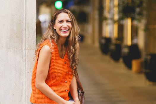 Happy latin beauty woman laughing at the camera sitting in the street