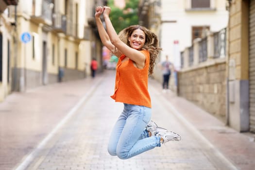 Full length portrait of a happy woman jumping in the street