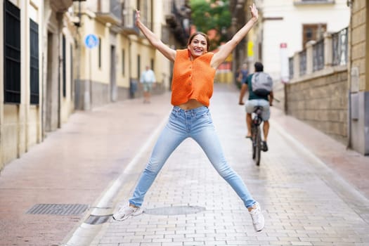 Full length portrait of a latin woman jumping happily in the city
