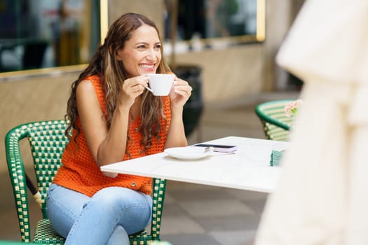 Latin beauty woman smiling while drinking coffee sitting on a terrace