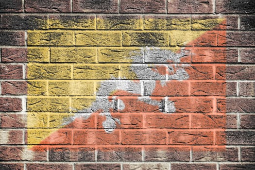 A Bhutan flag on a brick wall background yellow orange diagonal Druk Thander Dragon