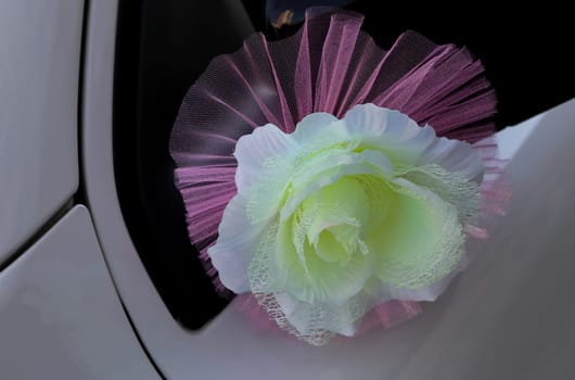 Decorative,wedding flower attached to the bride and groom's car door. Orange, green artificial flower.