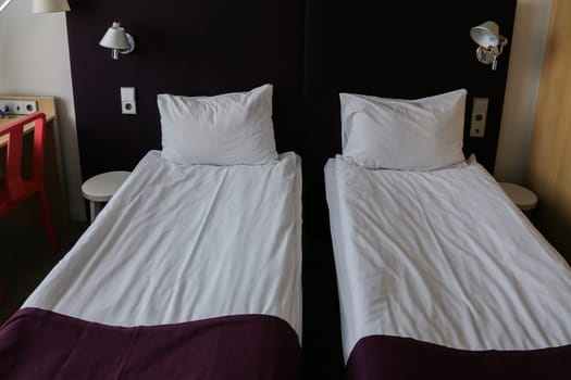 Two comfortable beds with clean, fresh linens in the room. Two comfortable beds with clean, fresh linens in the room. A bed with a white sheet, pillow and red blanket.