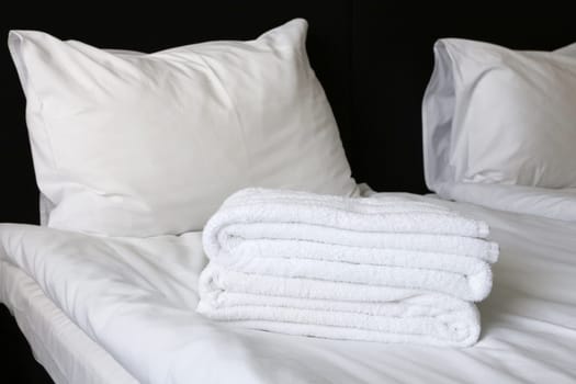 Two pillows on a bed covered with white linen, a sheet, towels. Bedroom in a hotel.