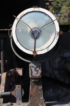 Close-up vertical photo of a spotlight lamp from an old, abandoned steam locomotive.