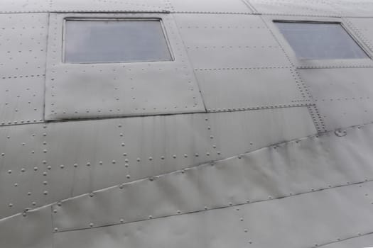 Windows in Airplane Fuselage. Two square fuselage windows on the side of an old green transport aircraft.