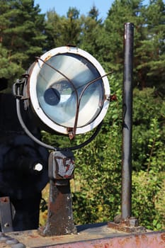 Vertical photo of a spotlight lamp from an old, abandoned steam locomotive.