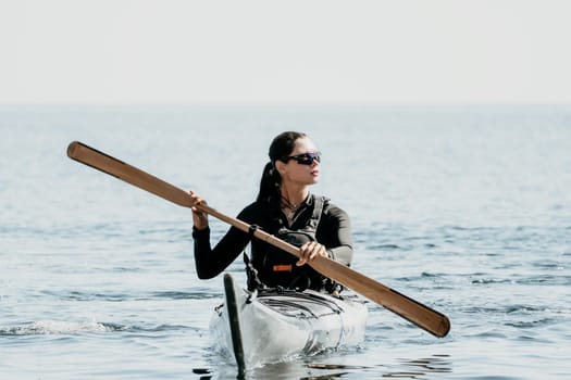 Happy smiling woman in kayak on ocean, paddling with wooden oar. Calm sea water and horizon in background