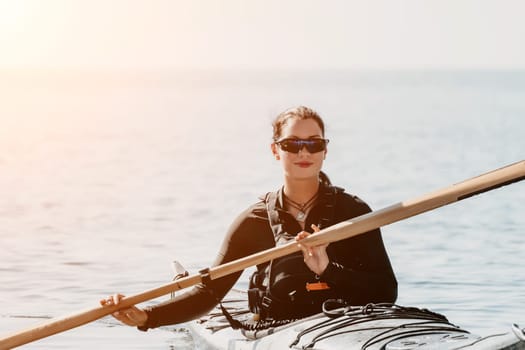 Happy smiling woman in kayak on ocean, paddling with wooden oar. Calm sea water and horizon in background