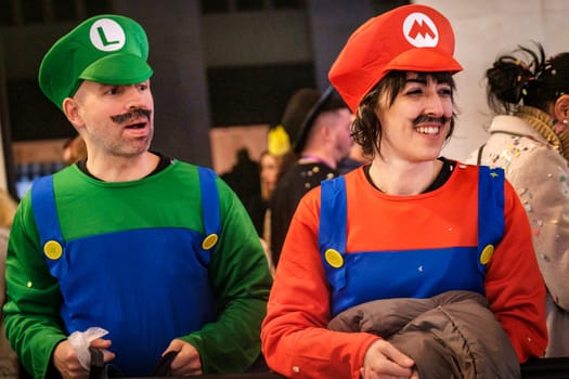 two people dressed up as characters commonly associated with the Mario video game franchise. On the left, someone is dressed in a green shirt, blue overalls, a green hat with an L on it, and a fake mustache, representing the character often known as Mario's brother